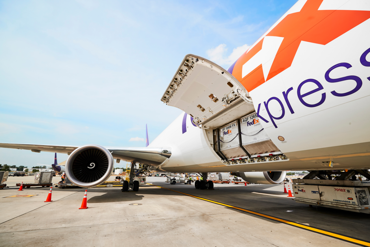FedEx cargo plane with its cargo door open during loading operations at the airport.