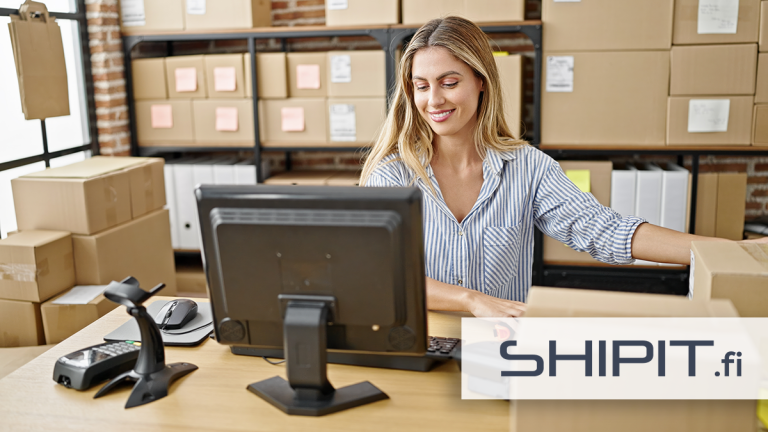 Nainen työskentelee pakettien keskellä verkkokaupan varastossa käyttäen Shipit.fi-lähetystyökalua.